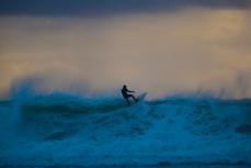 A surfer contemplates floating the end section during a dawn session at a remote Catlins' beach, Catlins, New Zealand. 