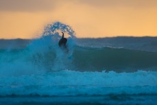 A surfer throws a fan of spray during a dawn session at a remote Catlins' beach, Catlins, New Zealand. 