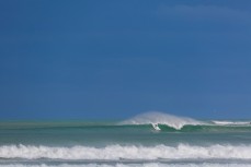 A surfer drops in during a once in a blue moon swell at a secret bank near Dunedin, New Zealand.