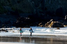 Surfers head out to make the most of calm, clean conditions at Blackhead Beach, Dunedin, New Zealand.