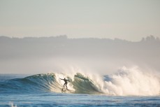 A surfer drops in to fun winter waves at Blackhead Beach, Dunedin, New Zealand.