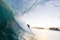 A surfer rides a fun winter wave at Blackhead Beach, Dunedin, New Zealand.