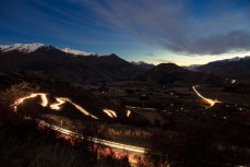 Car lights wind down the Crown Range in winter and head toward Queenstown, Central Otago, New Zealand.