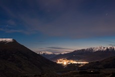 Car lights wind down the Crown Range in winter and head toward Queenstown, Central Otago, New Zealand.