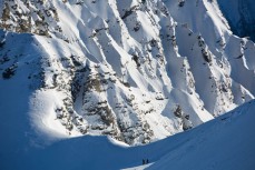 Backcountry skiers look for fresh lines on a bluebird day at Treble Cone Ski Resort, Wanaka, Central Otago, New Zealand.