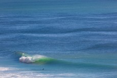 A surfer watches a wave break on the north coast at Aramoana, Dunedin, New Zealand.