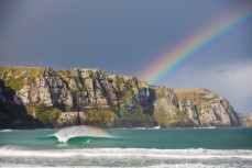 A rainbow illuminates a peak at a remote beach in the Catlins, Southland, New Zealand. 