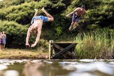 Rob and Justice take a jetty jump at Bethells Beach, Auckland, New Zealand.