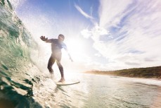 A surfer snags a lazy summer wave at Blackhead Beach, Dunedin, New Zealand.