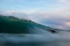 A surfer paddles into a fun wintry wave at St Kilda, Dunedin, New Zealand.