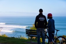 Ken Hansen and his daughter Nikau watch a solid swell at Raglan, Waikato, New Zealand.