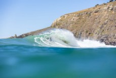 A large swell hits a point break near Dunedin, New Zealand.