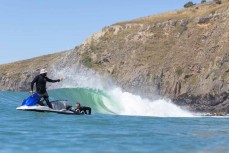Ski team chases waves at a point break near Dunedin, New Zealand.