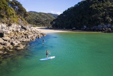 Paddleboarders explore Abel Tasman National Park on a stunning day on the water, Tasman, New Zealand.