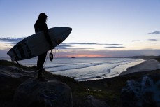 Taya Morrison watches the sunset on playful summer waves at Blackhead Beach, Dunedin, New Zealand.