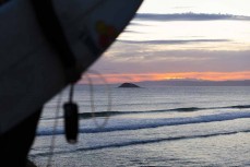 Taya Morrison watches the sunset on playful summer waves at Blackhead Beach, Dunedin, New Zealand.