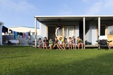 A group of kids eat dinner at a bach on the Mahia Peninsula near Gisborne, Eastland, New Zealand.