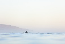 Surfers patiently wait for a set  during a late autumn swell at St Clair, Dunedin, New Zealand.