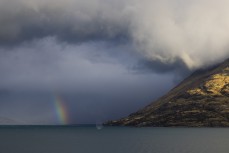 A summer storm causes a waterspout and rainbow across mountains and over Lake Wakatipu, Queenstown, Tahuna, Central Otago, New Zealand.