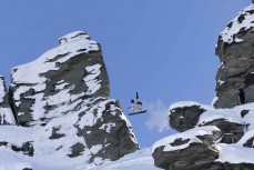 A snowboarder drops off a rock near the summit during a powder day at Treble Cone ski field, Wanaka, New Zealand.