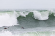 Surfers get cleaned up by a wide set during a spring swell at Manu Bay, Raglan, Waikato, New Zealand.