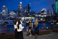 Friends pose for photos with the Auckland city skyline at dusk in the Wynyard Quarter near downtown Auckland, New Zealand.Photo: Derek Morrison