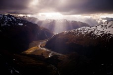 Afternoon light pierces cloud cover in Fiordland during a helicopter flight out of Big Bay, Fiordland National Park, Fiordland, New Zealand. 