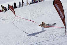 Zephyr Lovelock crosses the finishline first in the boardhouse snow skate during the Mini Pipe World Champs held in spring at Cardrona ski field, Cardrona Valley, Wanaka, New Zealand.