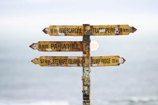 Weathered and stickered signpost at McCraken's Rest, Southland, New Zealand.Photo: Derek Morrison