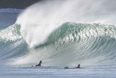 Surfers watch a peak at a remote beach break in the Catlins, New Zealand. Photo: Derek Morrison