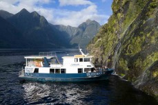 Tutoko II nudges under a waterfall during a tour exploring Doubtful Sound with Fiordland Expeditions Limited aboard the Tutoko II in Doubtful Sound, Fiordland, New Zealand. Photo: Derek Morrison