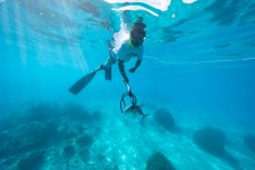 Sujud spears a blue trevally while diving between surfs in the Mentawai Islands, Sumatra, Indonesia.