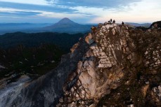 Climbers take in the sunrise from one of the crater summits of Mt Sibayak (2212m) near Bergastagi, Northern Sumatra, Indonesia.