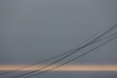 Powerlines arc across a placid horizon at St Clair Beach, Dunedin, New Zealand. 