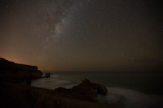 Starlight illuminates the night sky over Tunnel Beach, Dunedin, New Zealand. 