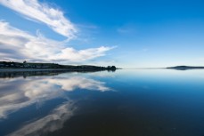 Calm water reflects the sky at Taieri Rivermouth, Dunedin, New Zealand.