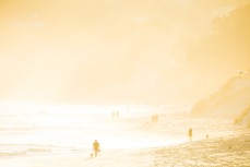 People walk in sunshine at St Kilda Beach, Dunedin, New Zealand. 