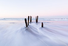 The South Pacific Ocean swirls through the lastr remaining remnants of the iconic poles at St Clair Beach, Dunedin, New Zealand. 