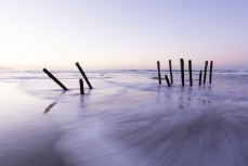 The South Pacific Ocean swirls through the lastr remaining remnants of the iconic poles at St Clair Beach, Dunedin, New Zealand. 